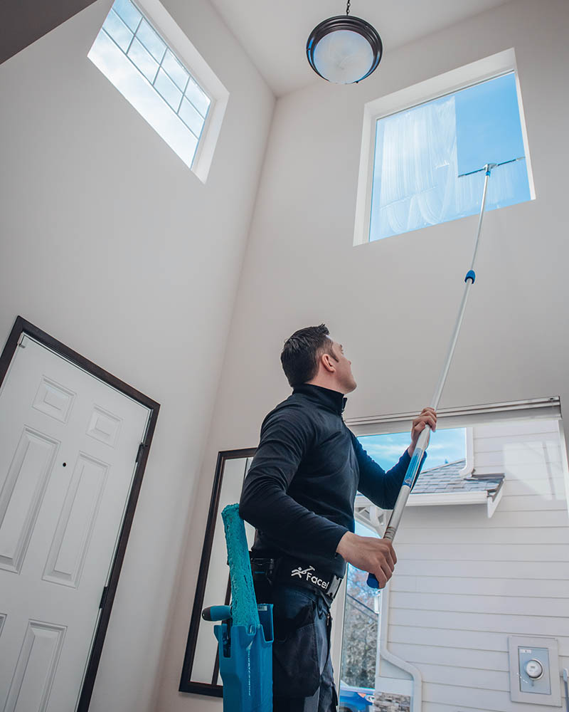 an emerald isle employee washes the interior windows of a client's entryway